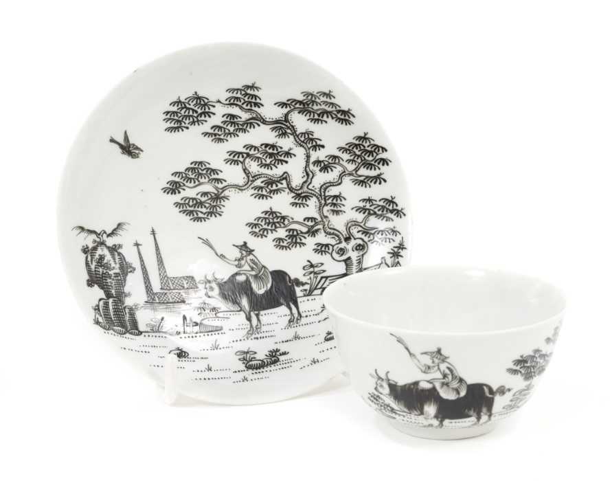 Lot 16 - A Worcester tea bowl and saucer, circa 1756, painted en grisaille with the Boy on a Buffalo pattern, painter's marks to bases, the saucer measuring 11.75cm diameter