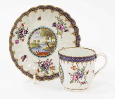 Lot 49 - A Worcester porcelain fluted coffee cup and saucer, circa 1780, of Dalhousie type, each painted with a landscape panel on a ground of floral sprays and insects within blue borders highlighted in gi...