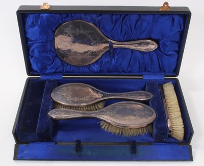 Lot 398 - George V silver backed dressing table set comprising hand mirror and three brushes with engraved floral and ribbon decoration, (Birmingham / Chester 1911)