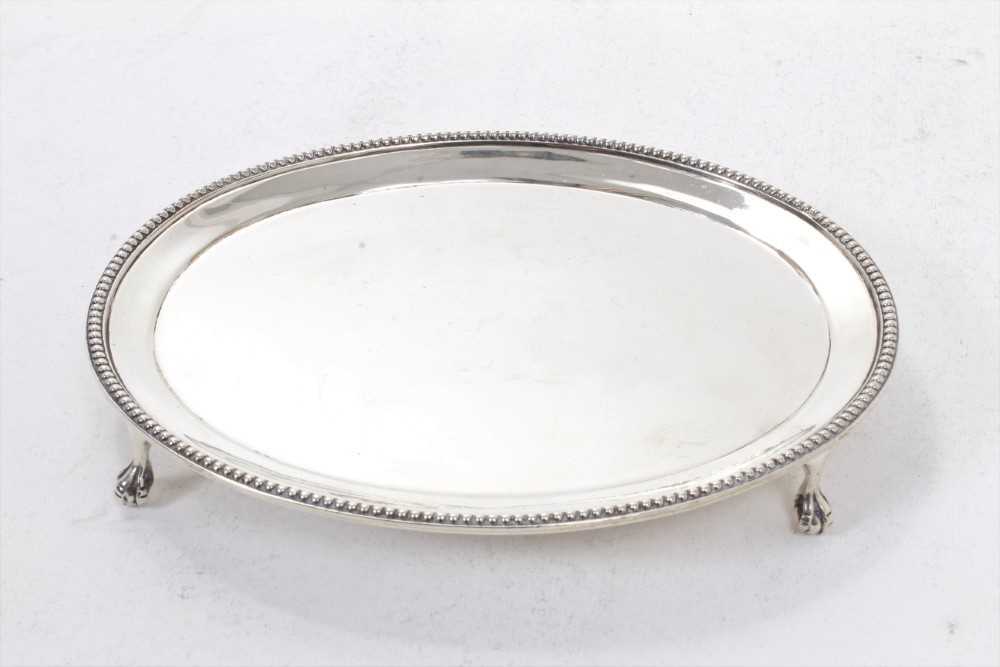 Lot 286 - Late Victorian silver card tray of oval form, with bead border, on four ball and claw feet