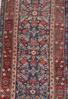 Lot 1477 - Antique Hamadan runner with all over floral motif in meander boarders on red and blue ground. 500cm long x 102cm wide