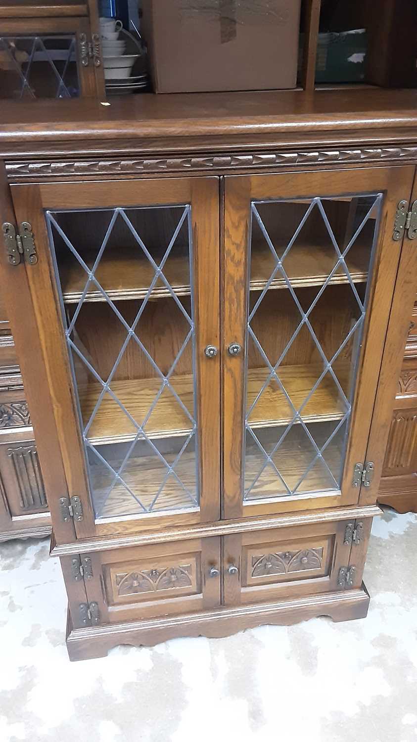 Lot 1143 - Old Charm oak bookcase with adjustable shelves enclosed by two leaded glazed doors with two carved panelled doors below, 80cm wide, 28cm deep, 127cm high