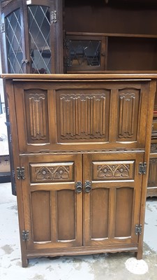 Lot 1144 - Old Charm oak cocktail cabinet with hinged rising lid and linenfold decoration, and two carved panelled doors below, 76cm wide, 37cm deep, 109cm high