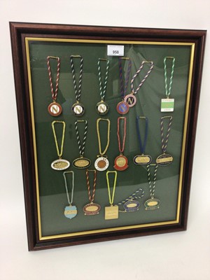 Lot 958 - Collection of seventeen metal and enamel race badges for Newmarket, one for Cheltenham, dating from 1992-2009, mounted on a display board in glazed frame, 55cm x 45cm overall