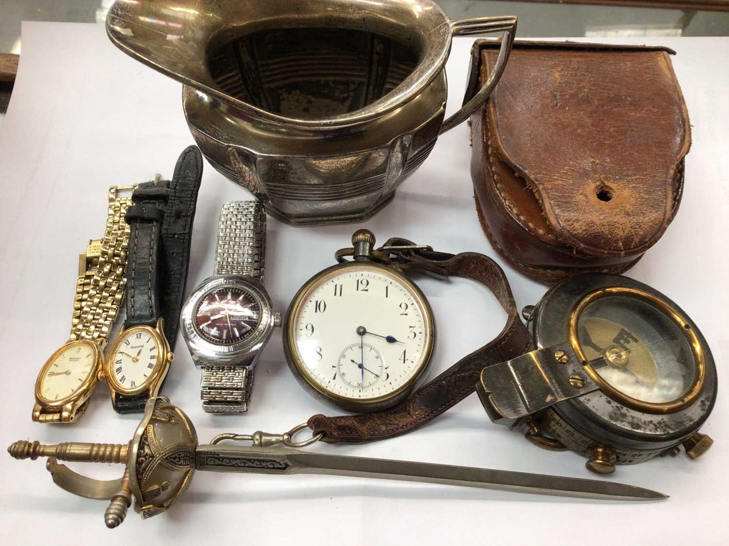 Lot 917 - Silver milk jug, pocket watch, compass in leather case, three wristwatches and a sword paper knife