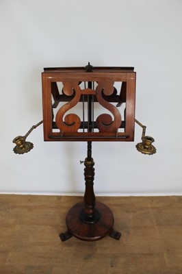 Lot 1357 - Early Victorian rosewood duet music stand, with twin adjustable pierced rests and flanking brass hinged candle arms raising on turned column and platform base on scroll feet, 125cm high