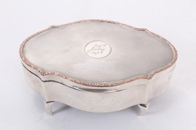 Lot 362 - George V silver jewellery box of shaped oval form with engine turned decoration, engraved date to central cartouche, hinged cover with silk and velvet lined interior, raised on four legs, (Chester...