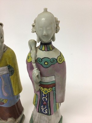 Lot 148 - Three Chinese porcelain figures of immortals, Qianlong period, each polychrome decorated and shown standing on square bases, the largest measuring 24cm high
