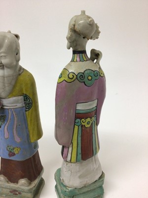 Lot 148 - Three Chinese porcelain figures of immortals, Qianlong period, each polychrome decorated and shown standing on square bases, the largest measuring 24cm high