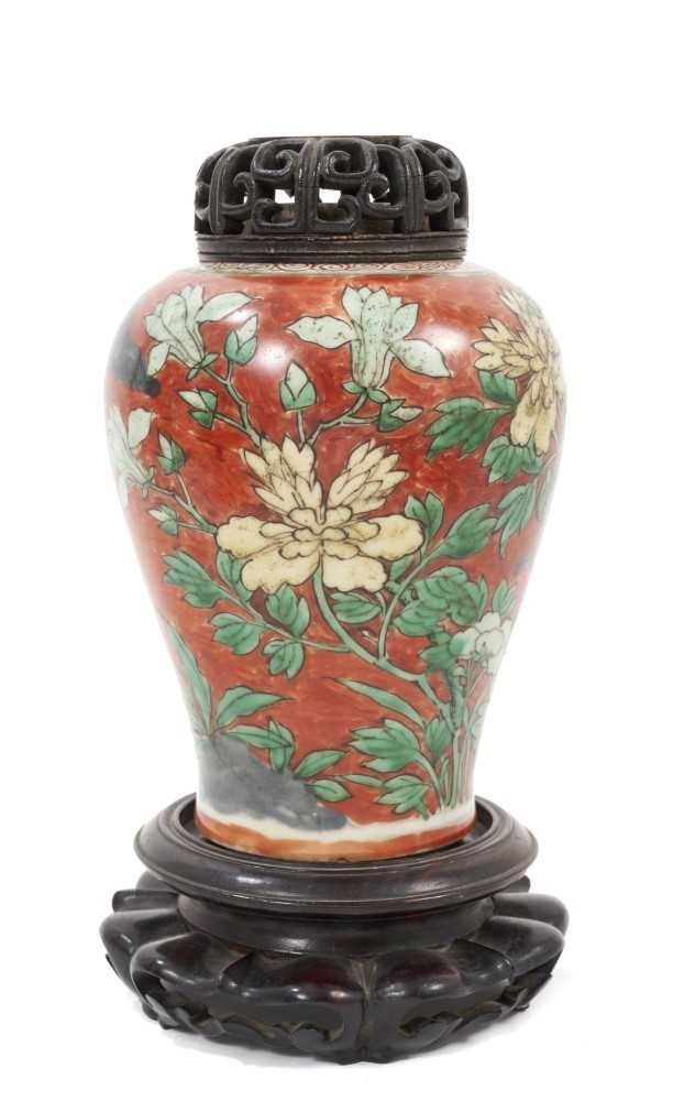 Lot 150 - Chinese Wucai baluster jar, 17th century, decorated with a bird in flight amongst rockwork and flowers, with carved wooden stand and cover, 16cm high without stand and cover