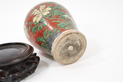 Lot 150 - Chinese Wucai baluster jar, 17th century, decorated with a bird in flight amongst rockwork and flowers, with carved wooden stand and cover, 16cm high without stand and cover