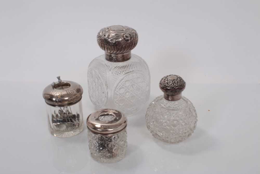 Lot 154 - Large Victorian silver topped cut glass scent bottle (Birmingham 1890) together with an Edwardian silver topped cut glass scent bottle (Birmingham 1902), and two silver topped hair tidies (4)
