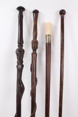 Lot 1017 - Edwardian walking stick with amethyst glass knop, ivory handled cane and two African hardwood canes with African head and snake decoration (4)