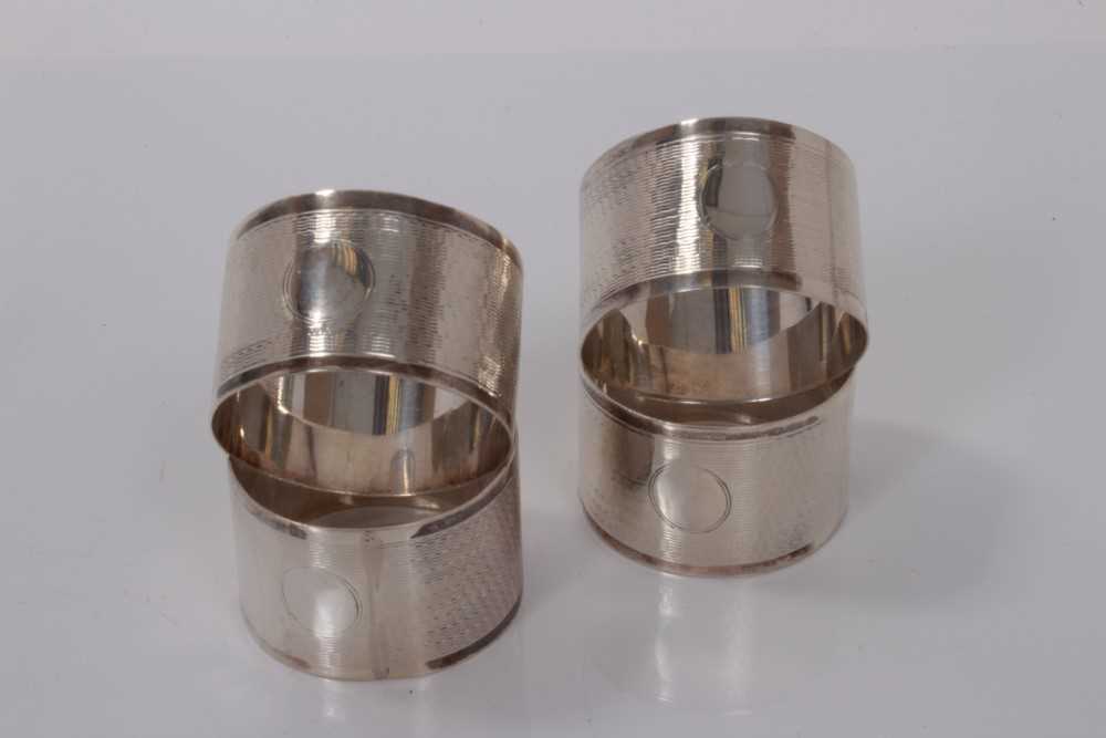 Lot 58 - Set of four George VI silver napkin rings with engine turned decoration, (Birmingham 1943), maker E J Houlston, all at 2.5ozs.