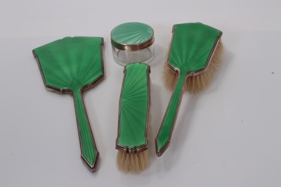 Lot 138 - George V silver hand mirror with green guilloche enamel decoration, together with two matching brushes, (Birmingham 1931), maker Aide Brothers, and a similar silver topped vanity jar (Birmingham 19...