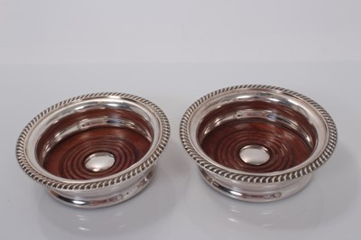 Lot 163 - Pair of Contemporary silver plated wine coasters by Barker Ellis, with gadrooned borders and wooden bases with inset silver plated discs to centres, 14.5cm in diameter.