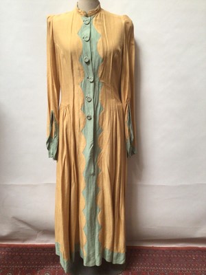 Lot 2093 - 1940s dress in gold and green crepe fabric with covered buttons, side gathering at waistline and shaped and gathered sleeves plud a 1950's black coat with wide shawl collar and diamond shape detai...