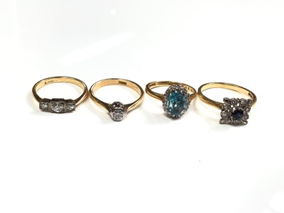Lot 109 - Four 18ct gold rings to include a three stone diamond ring, single stone diamond ring, blue zircon and diamond cluster ring and a sapphire and diamond cluster ring