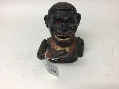 Lot 2420 - Early 20th century cast iron mechanical novelty money box/bank in the form of a gentleman in a black jacket with red collar, moveable arm, tongue and eyes. Base plate plug missing. 15cm overall hei...