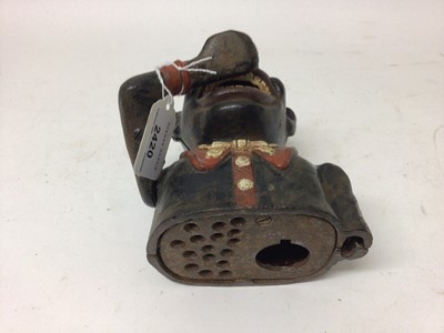 Lot 2420 - Early 20th century cast iron mechanical novelty money box/bank in the form of a gentleman in a black jacket with red collar, moveable arm, tongue and eyes. Base plate plug missing. 15cm overall hei...