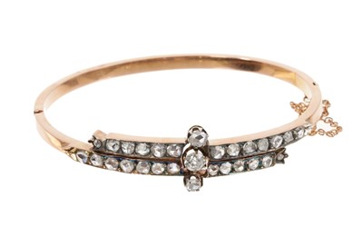 Lot 473 - Victorian diamond hinged bangle with a central old cut diamond flanked by two rose cut diamonds on a double row of further old cut diamonds in a cross-over design in silver and rose gold setting.