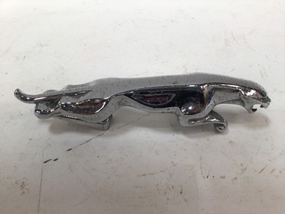 Lot 1970 - Chrome leaping Jaguar mascot, 19.5cm in length, together with two Jaguar wheel center caps and a vintage AA badge (4)