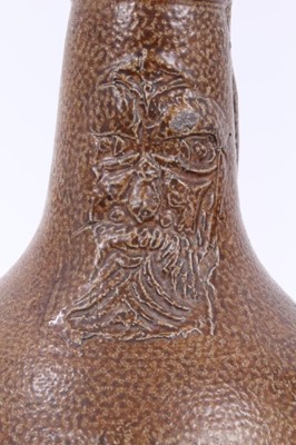 Lot 10 - A 17th century German stoneware Bellarmine jug, decorated with a mask and coat of arms, 23cm high