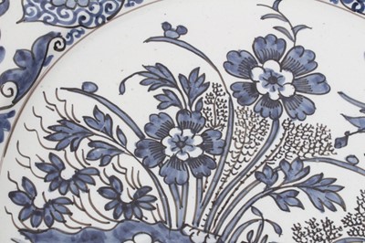 Lot 13 - A blue and white Dutch delftware dish, circa 1700, painted in the Oriental style with birds amongst flowers, with a foliate-patterned border, GK mark to base for Gerrit Kam, 34cm diameter