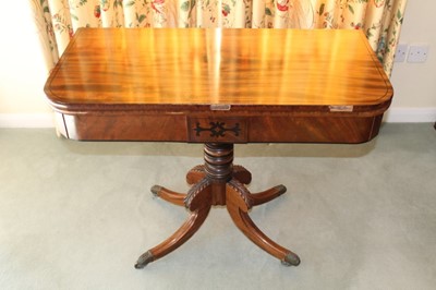 Lot 1246 - Regency mahogany card table with rounded rectangular fold-over top, on turned column and four carved splayed legs with brass capped castors, 93cm x 45cm