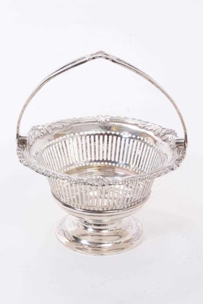 Lot 265 - Edwardian silver swing handled dish of small proportions, with pierced decoration and stylised shell/feather borders