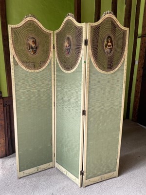 Lot 1223 - Decorative painted three fold boudoir screen with shield shape caned panels each painted with an oval portrait of a lady in costume, green silk panels below, 137cm wide x 180cm high