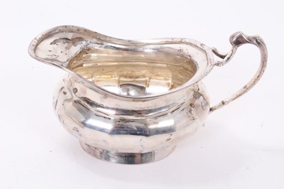 Lot 305 - George V silver milk jug of cauldron form, with faceted decoration and scroll handle, together with a matching sugar bowl, (Sheffield 1926), maker Lee & Wigfull, all at 15.5ozs, milk jug 15cm acros...