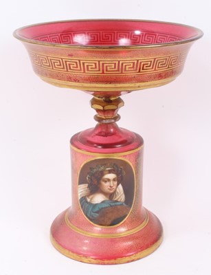 Lot 152 - A late 19th century Bohemian cranberry glass centrepiece, the circular bowl with gilt Greek Key pattern, above a pedestal base with gilt patterns and oval painted portrait of a young woman, 33.5cm...