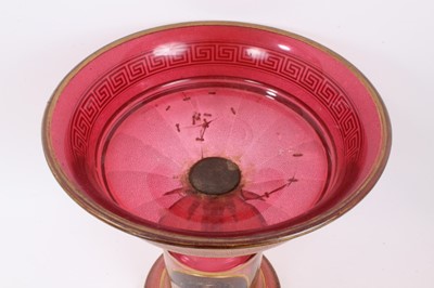 Lot 152 - A late 19th century Bohemian cranberry glass centrepiece, the circular bowl with gilt Greek Key pattern, above a pedestal base with gilt patterns and oval painted portrait of a young woman, 33.5cm...