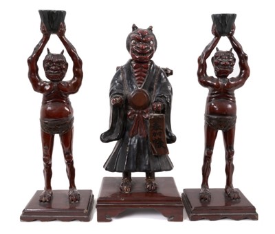 Lot 851 - Unusual 19th century Japanese red and black lacquer figure of a horned demon with glass eyes holding a scroll on platform base and pair similar demon candlesticks 45-47 cm (3)