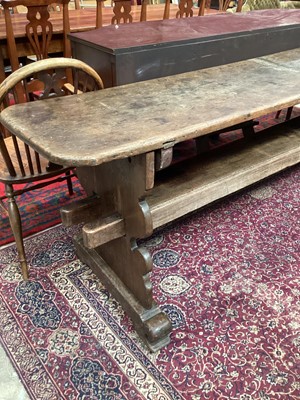 Lot 1370 - Highly unusual ecclesiastical oak refectory table/monks bench, probably 17th century, with massive single plank top raised on shaped trestle ends united by a substantial foot stretcher, 275 x 54cm