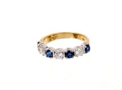 Lot 647 - Sapphire and diamond eternity ring with a half hoop of four round mixed cut blue sapphires and three round brilliant cut diamonds in claw setting on 18ct yellow gold shank