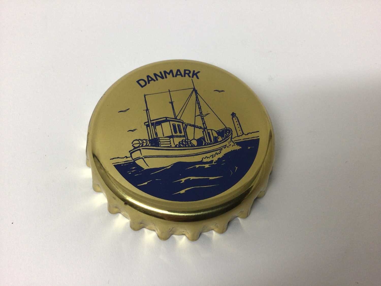 Lot 108 - Georg Jensen novelty bottle opener in the form of an oversized bottle cap, decorated with a boat