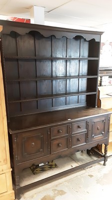 Lot 1256 - 1920's oak two height dresser with shelves above, two central drawers below flanked by two geometric panelled doors on turned front legs joined by stretchers, 151cm wide, 50cm deep, 206cm high