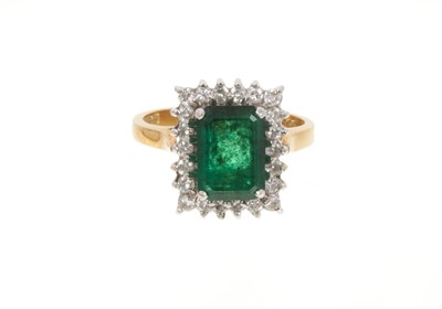 Lot 688 - Emerald and diamond cluster ring with a rectangular step cut emerald surrounded by brilliant cut diamonds