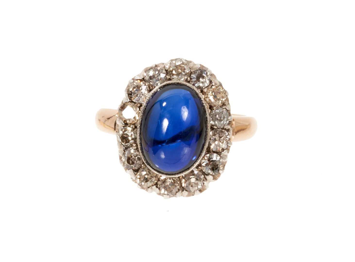 Lot 638 - Antique diamond and synthetic sapphire ring with an oval cabochon synthetic blue sapphire surrounded by a border of old cut diamonds