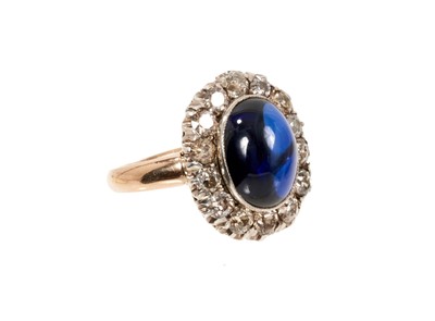 Lot 638 - Antique diamond and synthetic sapphire ring with an oval cabochon synthetic blue sapphire surrounded by a border of old cut diamonds