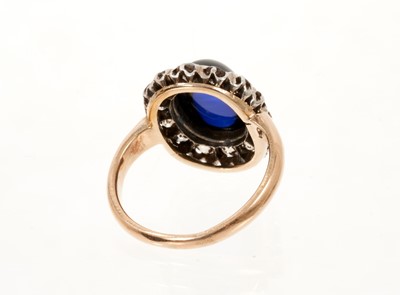 Lot 638 - Antique diamond and synthetic sapphire ring with an oval cabochon synthetic blue sapphire surrounded by a border of old cut diamonds