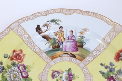 Lot 206 - A large pair of Dresden porcelain dishes, early 20th century, of scalloped form, decorated with figural panels on pink and yellow grounds, 'AR' marks to bases, 36cm diameter