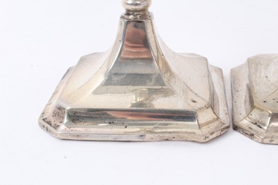 Lot 427 - Pair George V silver candlesticks with tapering octagonal stems and inverted bell candleholders, on octagonal pyramid bases, loaded (Birmingham 1918) Henry Williamson Ld. 26cm overall height.