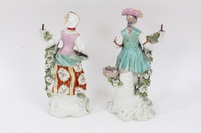 Lot 233 - A pair of Derby figural candlesticks, late 18th century, each standing next to floral encrusted tree trunks, on scrollwork bases, 26cm high