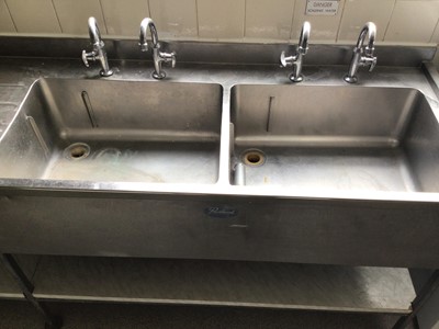 Lot 39 - A Portland stainless steel double bowl sink unit, with two pairs of taps and draining board, laminate shelf under, 2140 mm