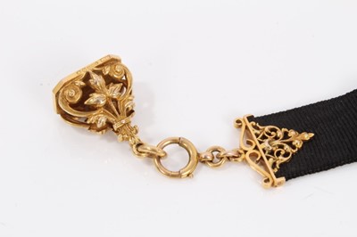 Lot 727 - Edwardian 9ct gold fob with leaf and scrolls, suspended gold mounted black silk ribbon, London 1909, overall length 18.5cm.
