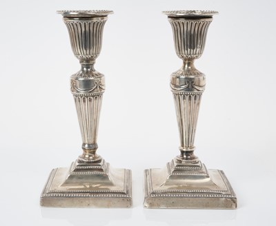 Lot 534 - Pair of Victorian silver candlesticks with inverted bell shaped candle holders, removable sconces and tapered columns on square bases with beaded borders, (London 1879), maker Thomas Bradbury & Son...