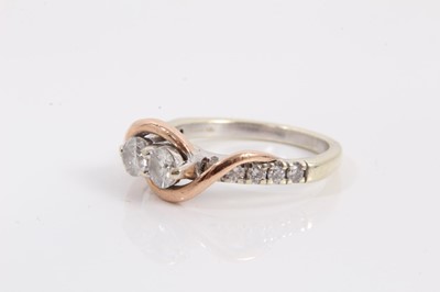 Lot 74 - 14ct white gold diamond two stone ring with rose gold crossover setting and further diamond set shoulders